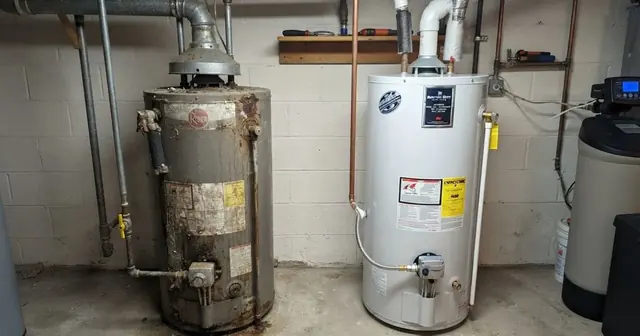 An older rusted gas water heater standing beside a clean new tank in a basement utility room